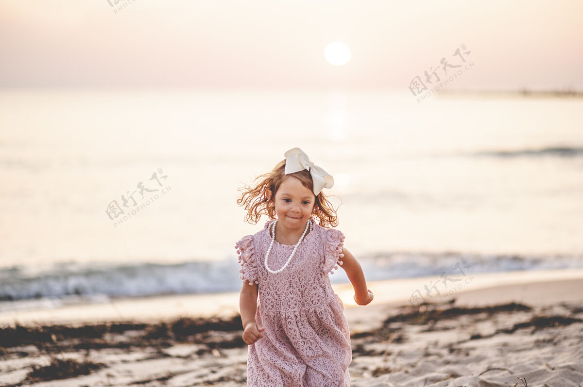 白种人海滩上一个金发小女孩的浅焦镜头小跑步浅