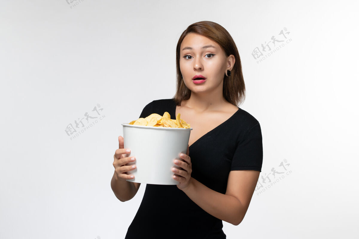 剧院正面图：年轻的女性拿着土豆片篮子 在浅白的表面上摆姿势浅白色电影黑发
