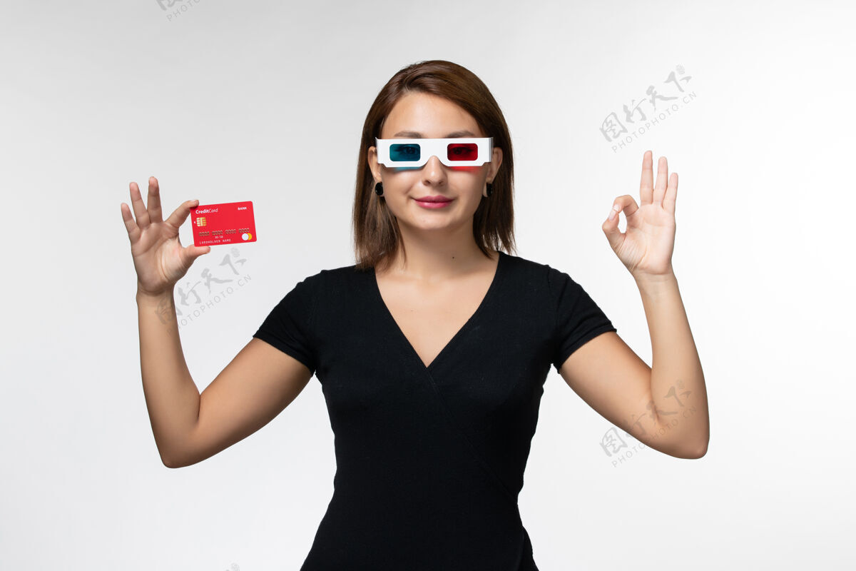 年轻女性正面图年轻女性手持银行卡 戴着d型太阳镜 白色表面银行前面太阳镜