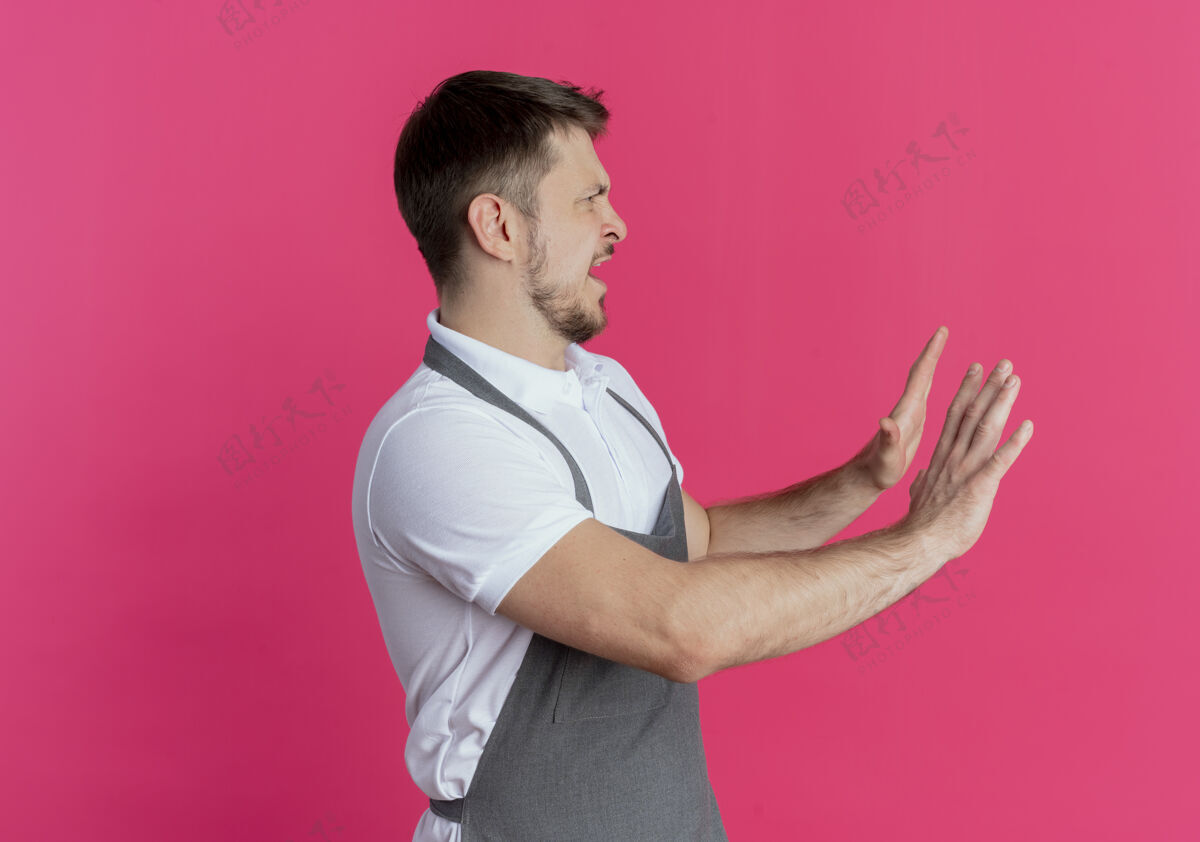 围裙围裙上的理发师站在粉红色的墙上 一边看一边喊着停下来手势靠边手