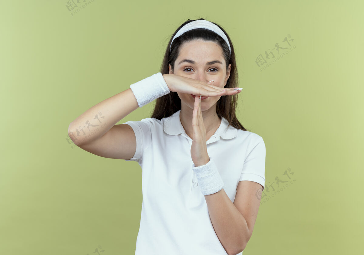 光戴着头巾的年轻健身女士做着暂停的手势 双手站在轻墙上站手女人