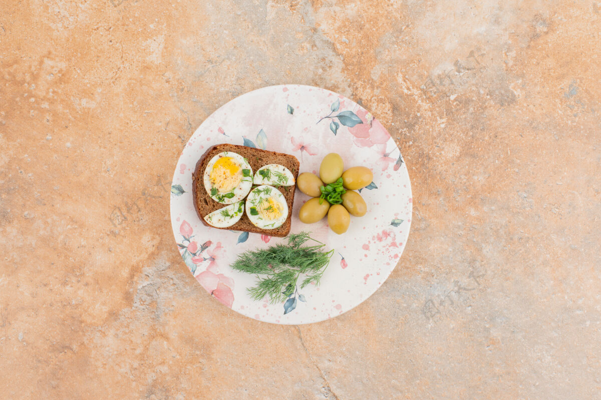 生的烤面包加煮鸡蛋 橄榄放在白盘子里绿的面包橄榄