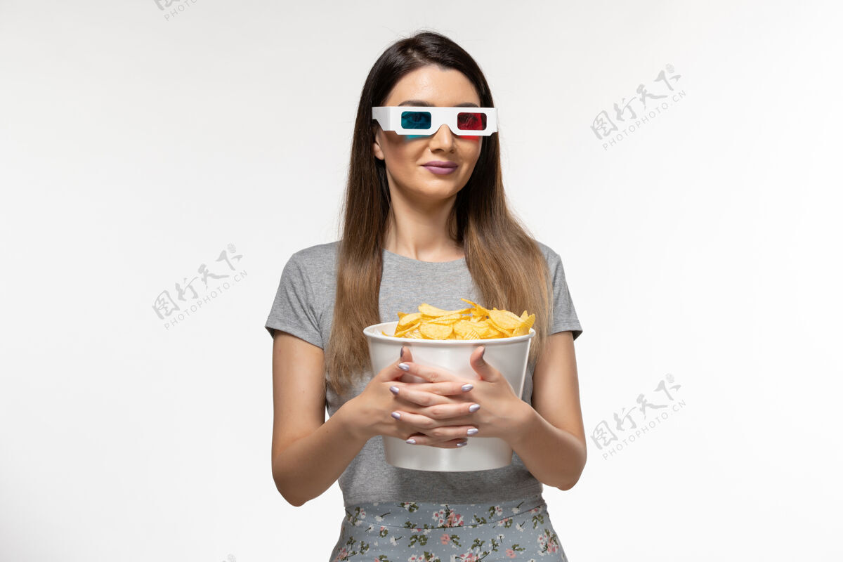 芯片正面图：年轻女性手持芯片 戴着d型太阳镜在白色表面看电影女看孤独