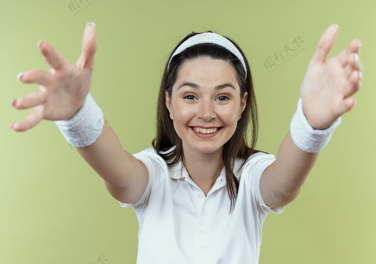 女人戴着头巾的年轻健身女士开心而积极地站在光墙上做欢迎手势健身积极轻