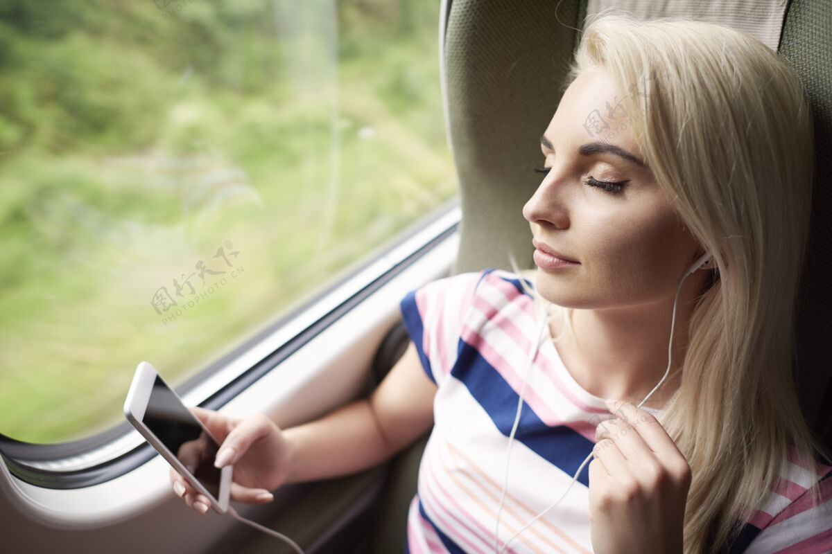 坐着女人放松与好音乐闭着眼睛旅行休闲服