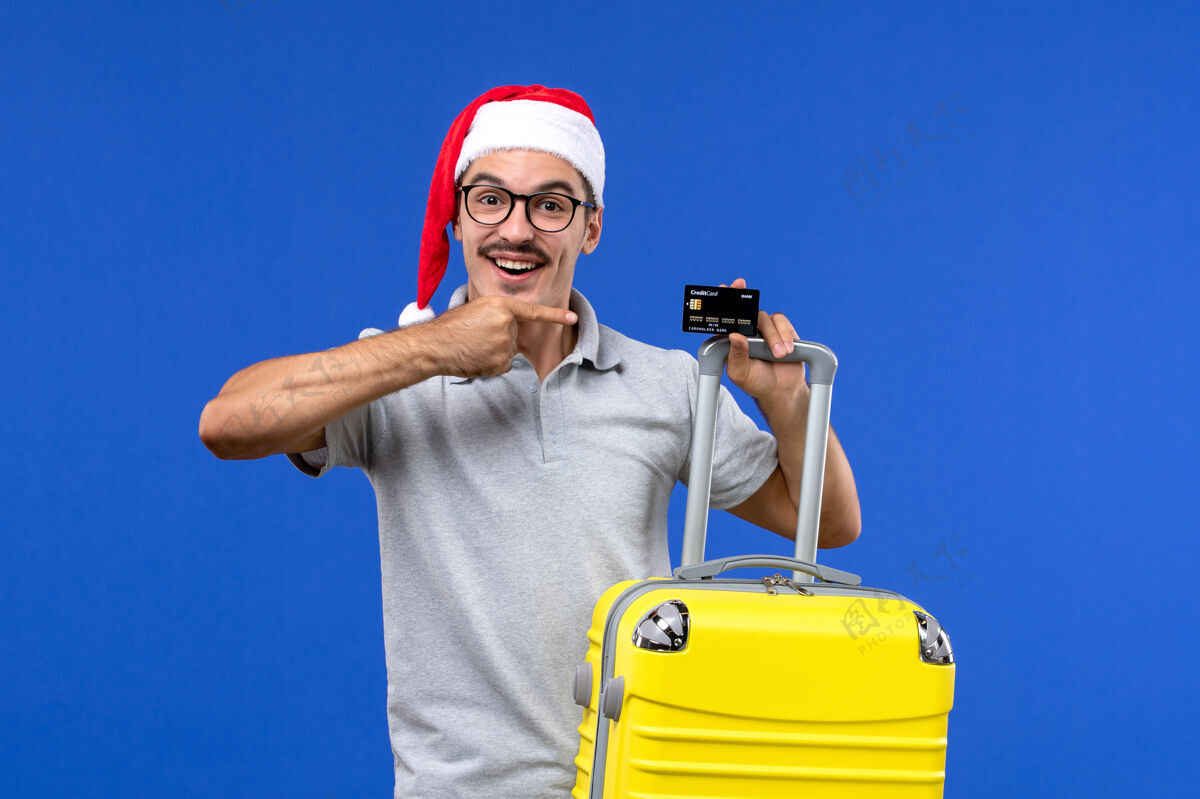 头盔正面图年轻男子手持黄包银行卡在蓝色背景下旅行度假感慨人承包商包
