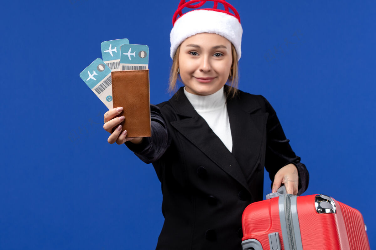年轻女性正面图：年轻女子拿着蓝色背景的机票包度假飞机工程师人