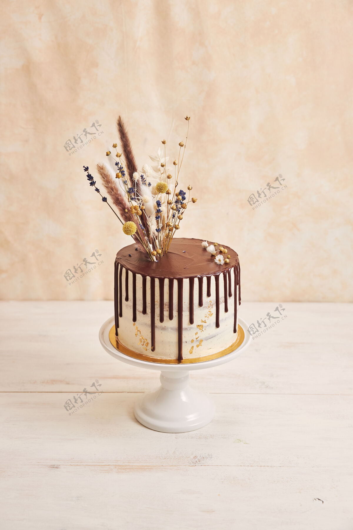 餐厅垂直拍摄美味波西米亚蛋糕与巧克力滴和鲜花上的黄金装饰美味盘子糕点
