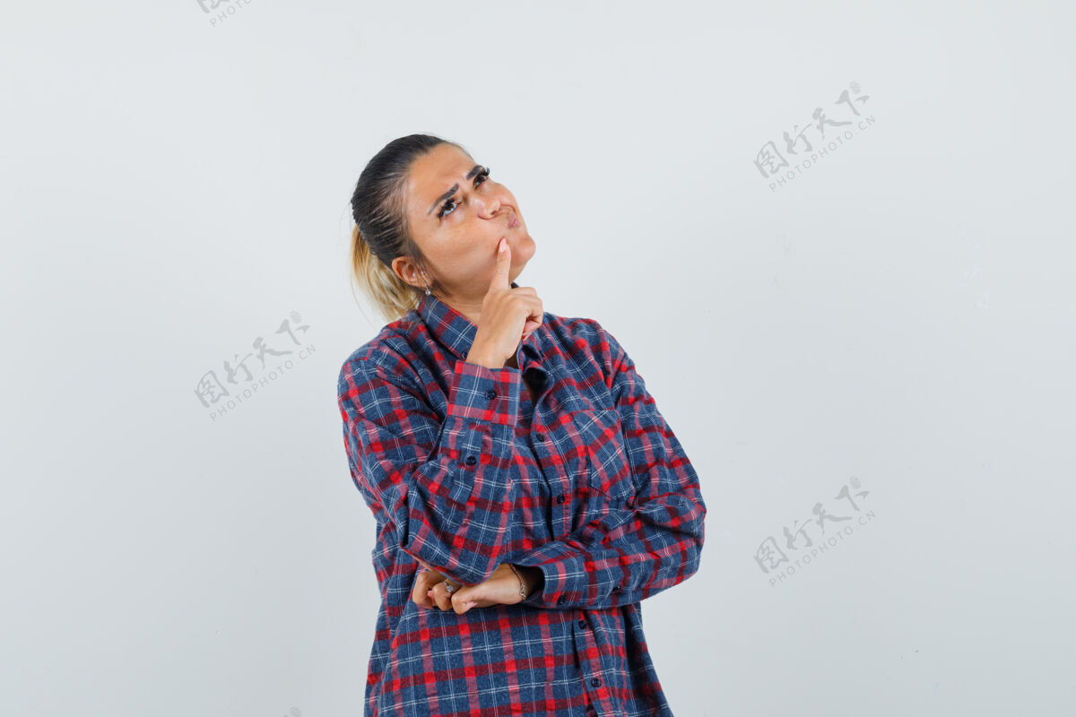 成人年轻女子站在思考的姿势 把食指放在下巴在格子衬衫和期待沉思 前视图黑发思考头发
