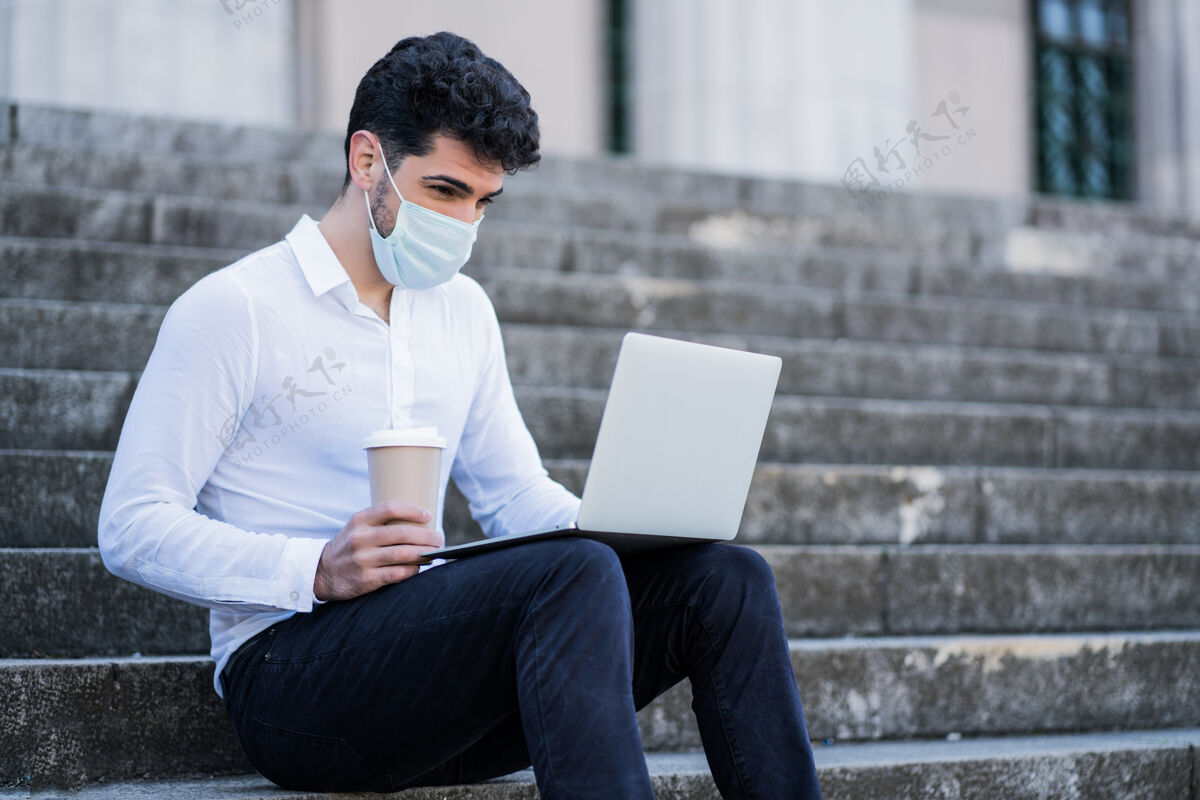 专业人士戴着口罩 坐在室外楼梯上使用笔记本电脑的商人肖像商业概念新的正常生活方式概念企业城市工作