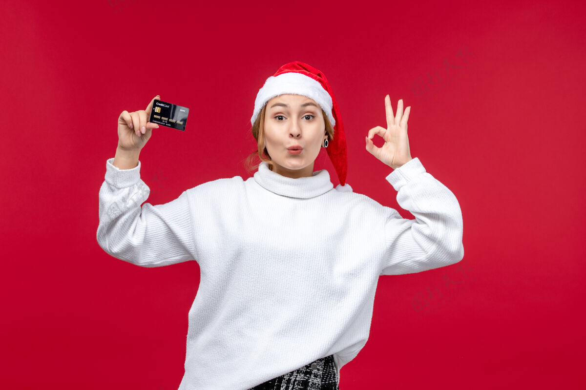 男性正面图 年轻女子手持红色背景的银行卡钱圣诞节欢乐