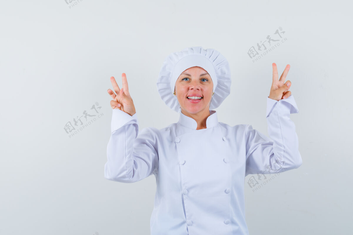 卷发身着白色制服的女厨师 展示v型标志 看起来很自信制服乐趣学生