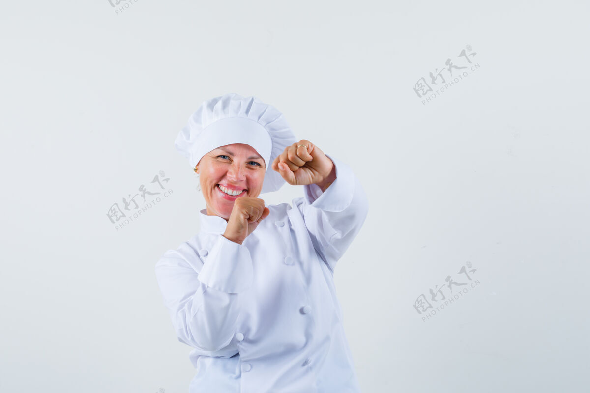 时尚一位身穿白色制服的女厨师摆出获胜者的姿势 看上去很快乐时尚人物快乐