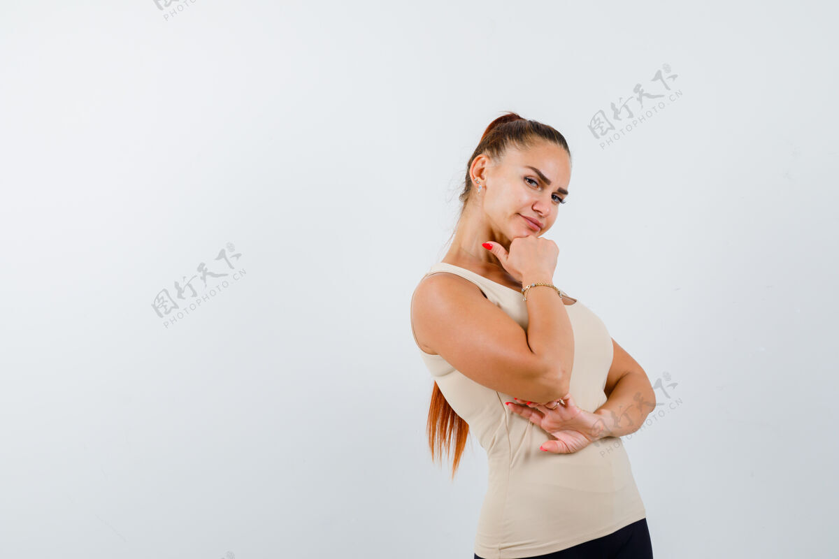 女性身着米色背心的年轻女性下巴下握有拳头 看上去自信满满 俯瞰前方休闲办公室女孩