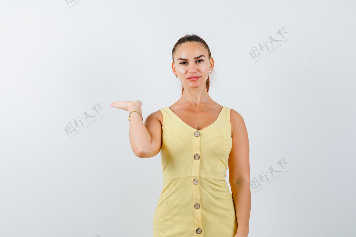 女性一个穿着黄色衣服假装拿着东西的年轻女人 看起来很自信年轻人微笑工作