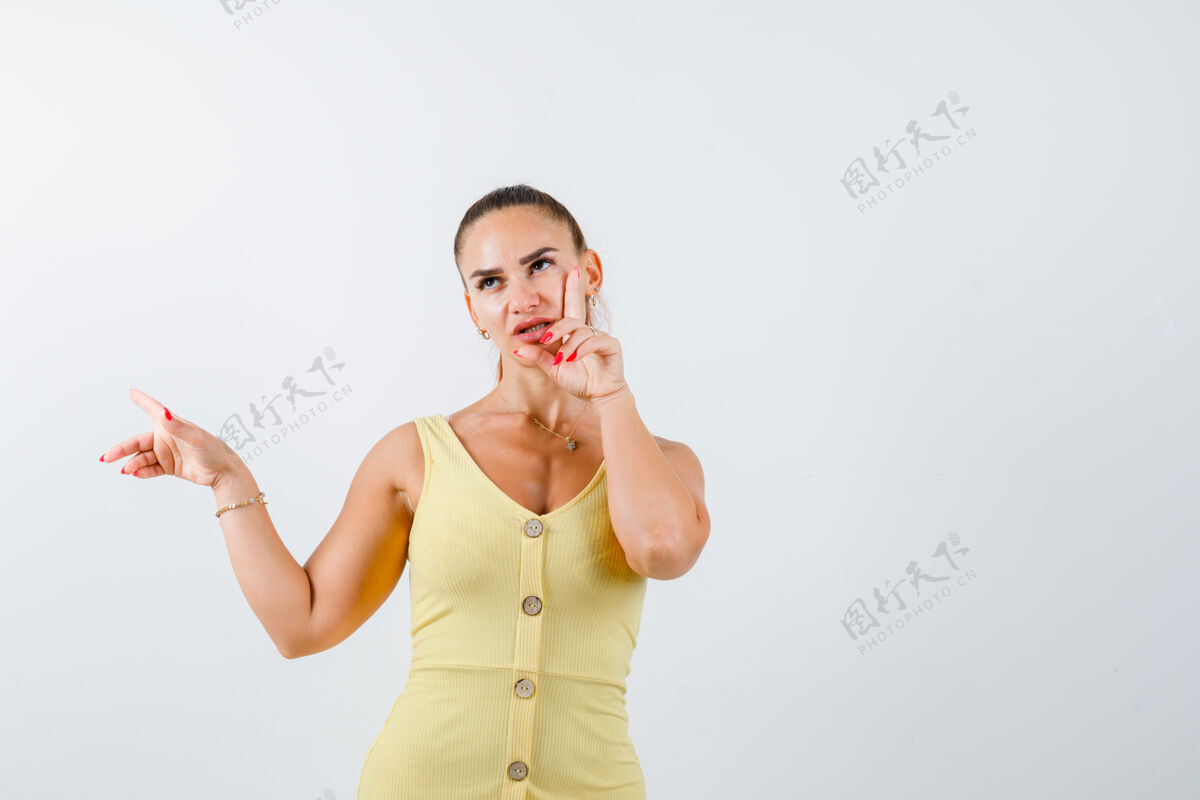 女人一幅年轻女子的肖像画 她指着左边 手指放在脸颊上 身着黄色连衣裙 面带沉思的神情头发手指人