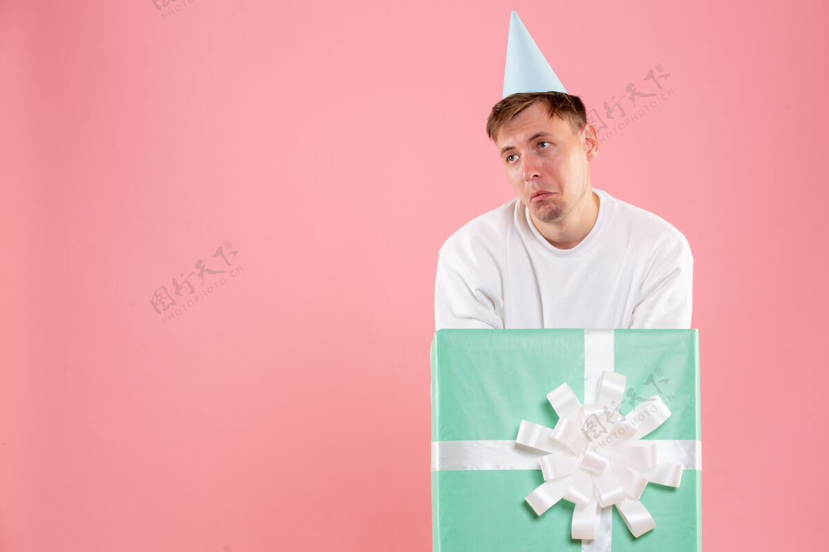 年轻男性正面图年轻男性在粉色背景上现在感到悲伤男人圣诞节礼物