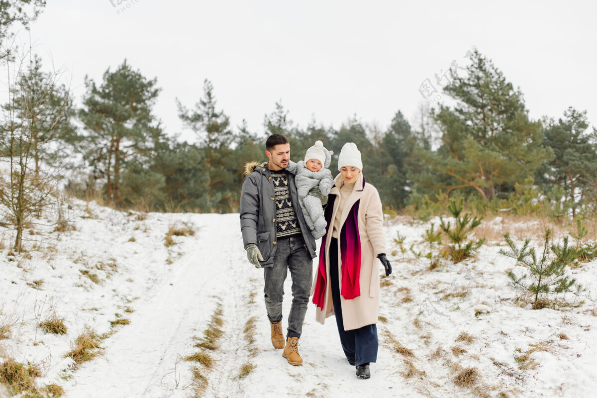 户外在一个阳光明媚的日子里 一家人在雪中散步 在冬季公园里玩得开心 互相拥抱 面带微笑玩耍雪快乐