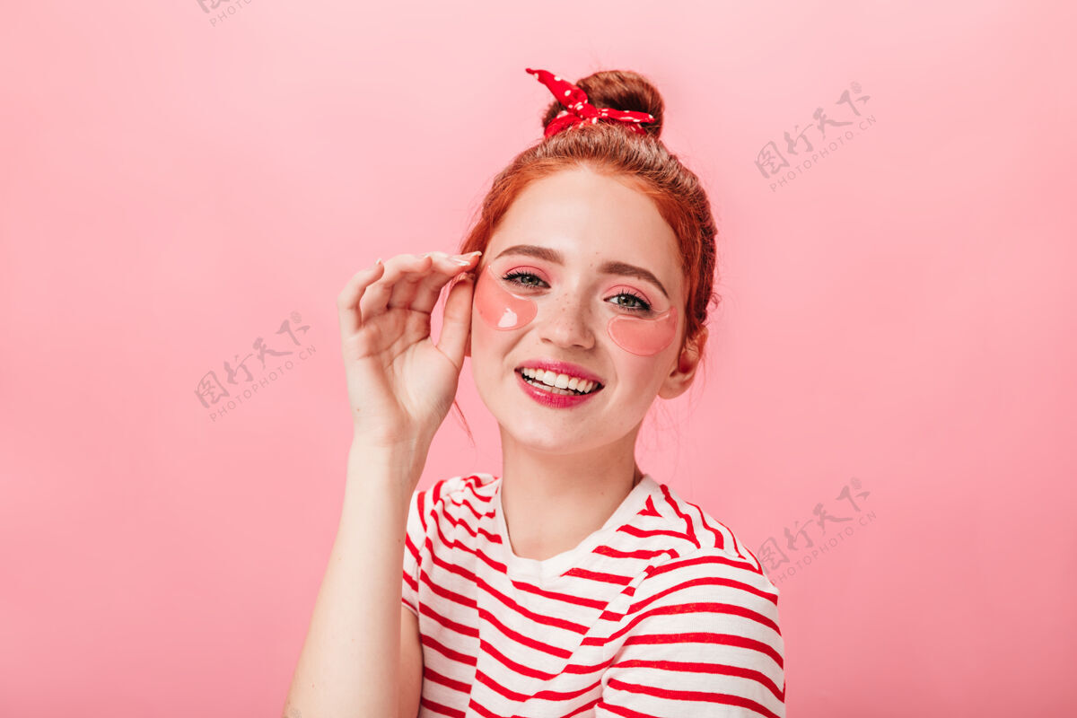 美女戴着眼罩的快乐年轻女子看着相机摄影棚拍摄的粉红色背景下 兴奋的姜汁女孩在做护肤护理女性护理女士