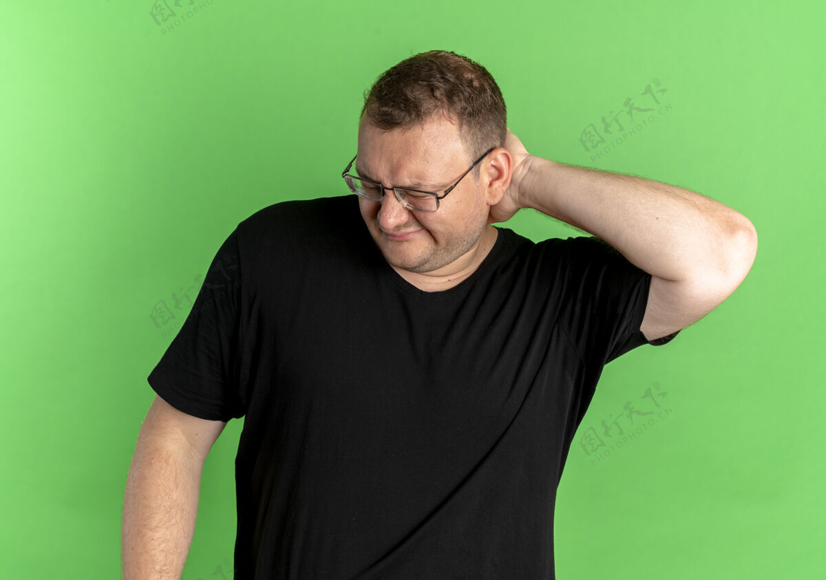 T恤戴眼镜的超重男子身穿黑色t恤 看上去对绿色迷惑不解看站男士