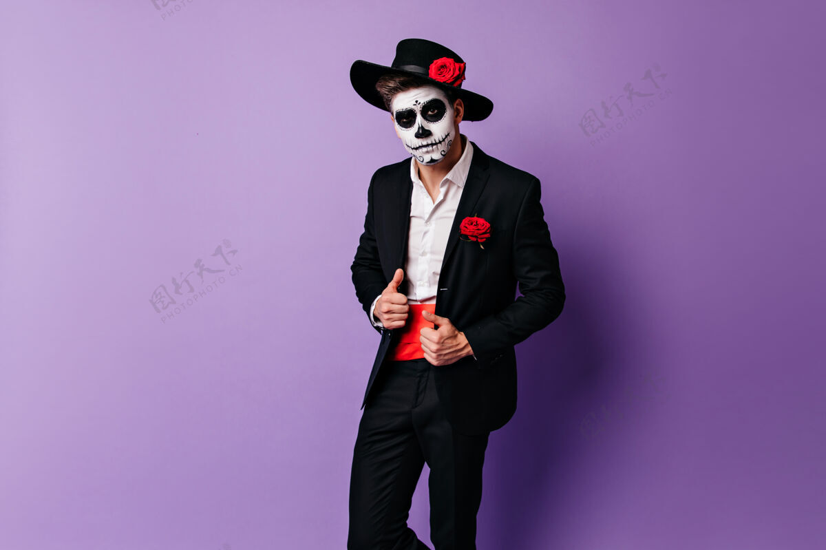 室内自信的僵尸家伙和戴着帽子的玫瑰合影有兴趣的男人带着骷髅妆准备万圣节派对的室内照片拉丁语死亡之日骷髅