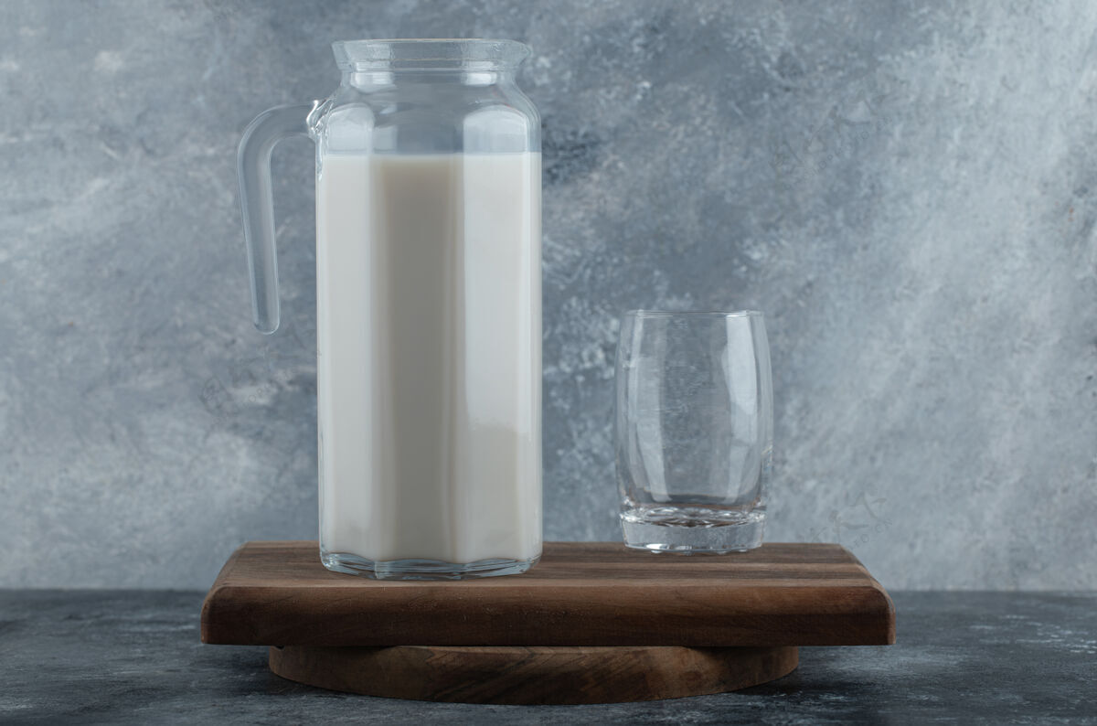 罐子一壶鲜奶和一杯水放在木板上满的产品饮料