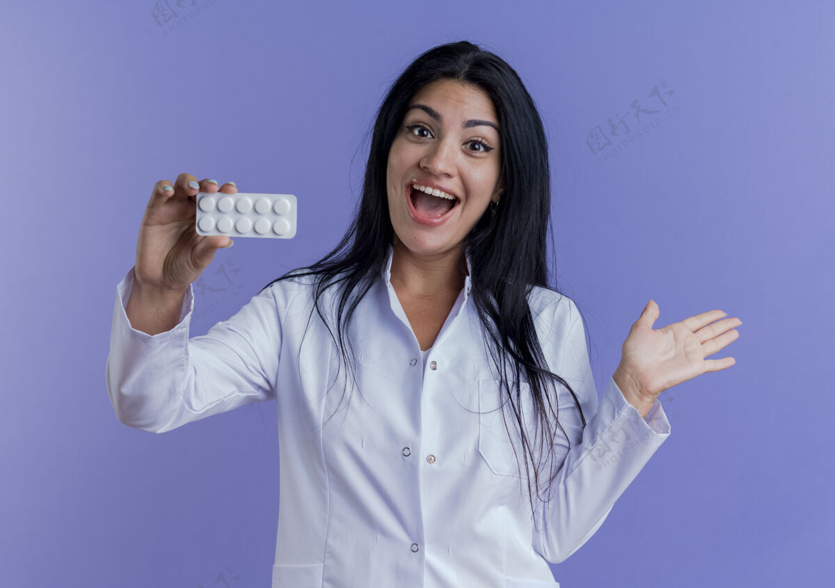 女人印象深刻的年轻女医生穿着医用长袍展示着一包药片 眼神中露出空手年轻包紫色