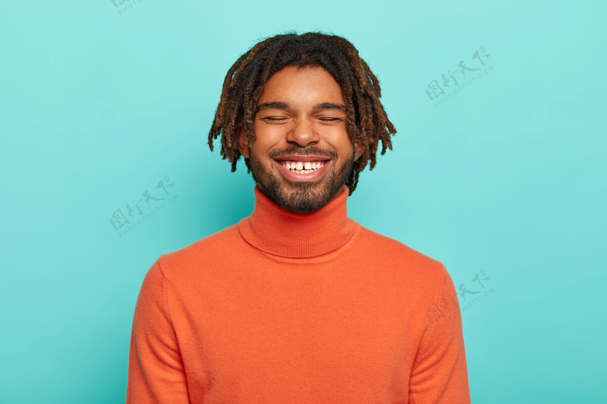 穿着无忧无虑的微笑的家伙有快乐的面部表情 对积极的事情笑 露出白色的牙齿 穿着橙色的马球衫无忧无虑男性欣喜若狂