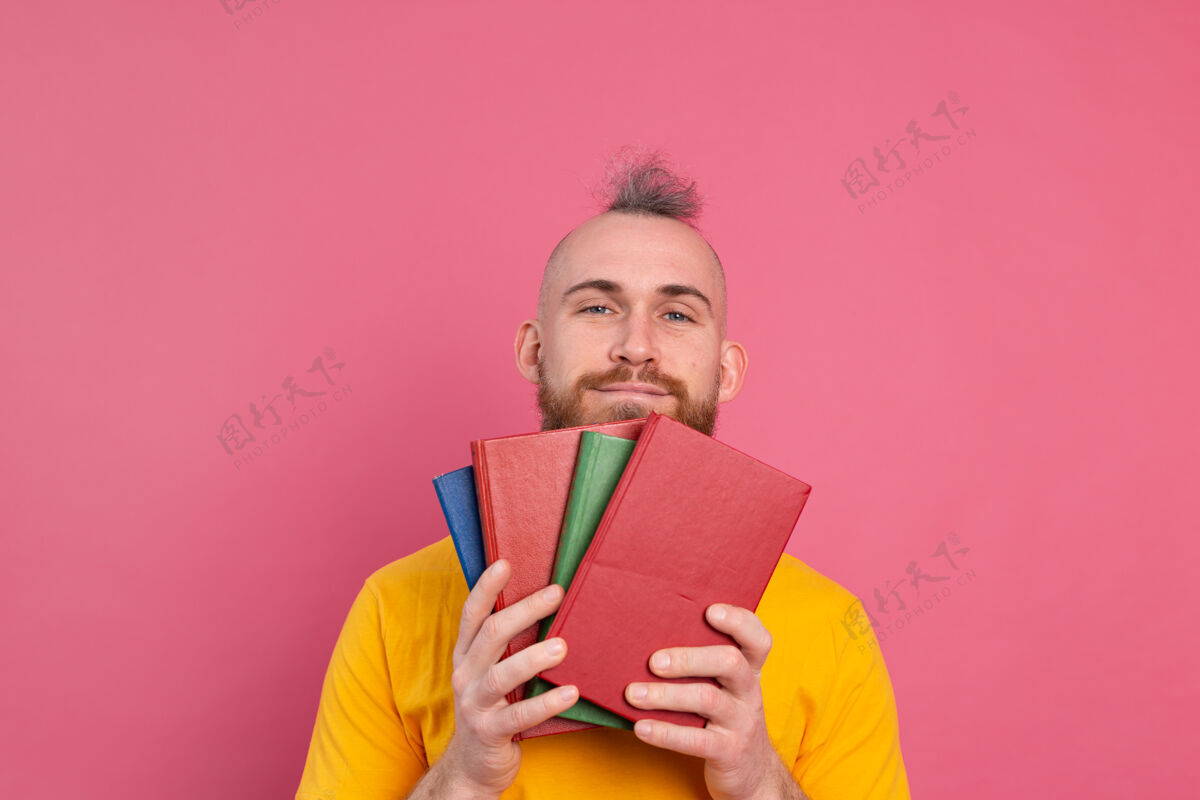 喜爱满脸笑容的成人休闲装 留着胡子的家伙拥抱着自己最喜欢的书 把自己孤立在粉色上快乐积极大学
