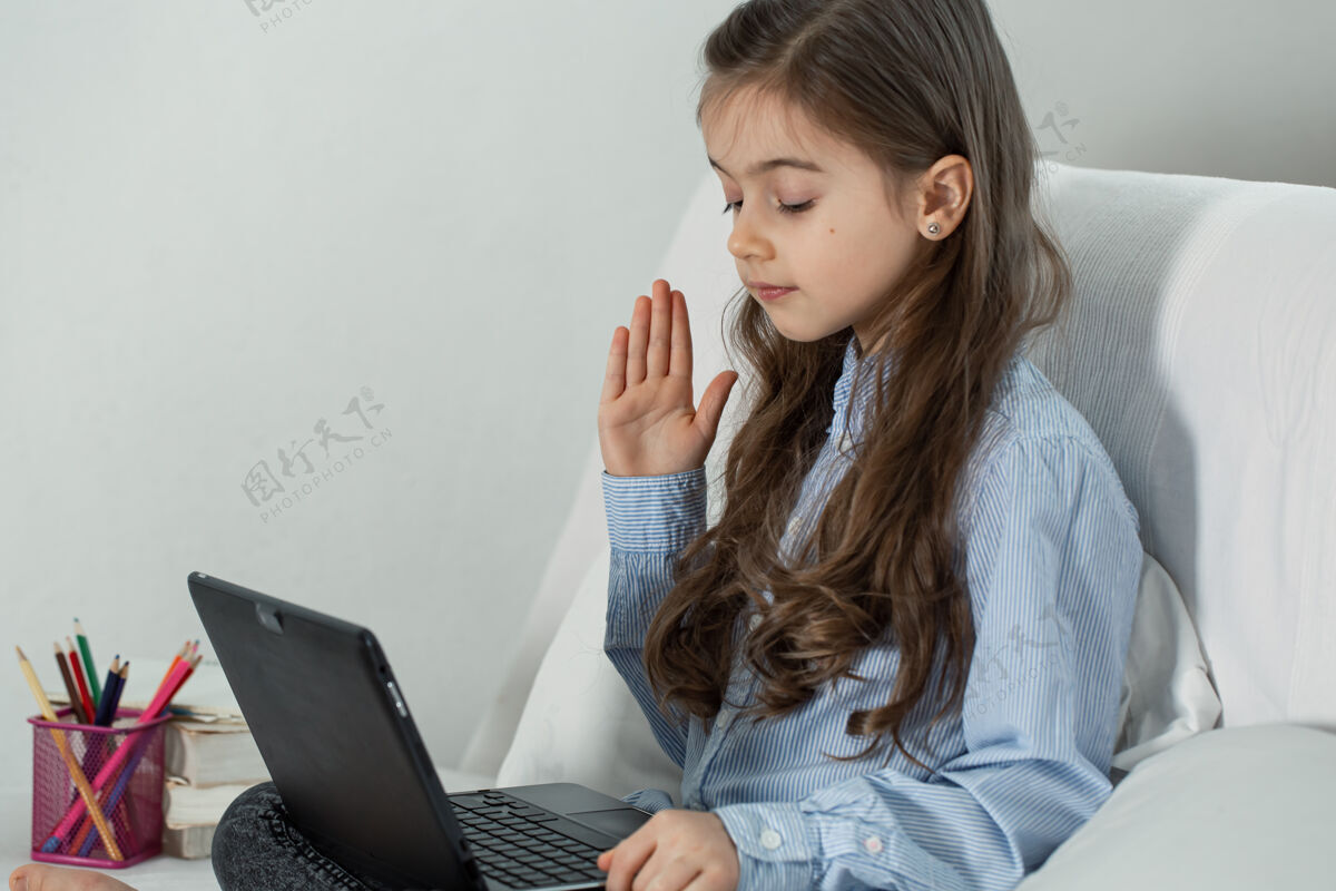 孩子由于冠状病毒大流行 一名小学女生在隔离期间远程使用笔记本电脑在家学习学习课程房子