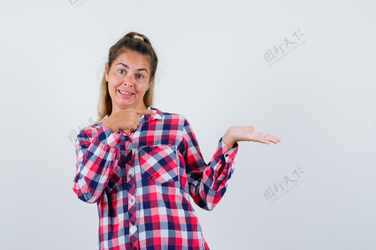 衬衫年轻的女士指着一件装在格子衬衫里的东西 看上去很高兴正视图脸成人视图