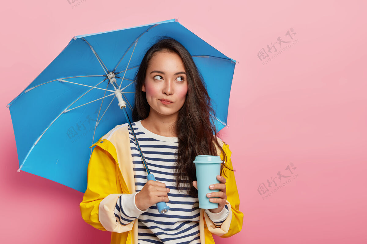 女人亚洲模样的沉思少女 雨天在雨伞下散步 喝外卖咖啡秋天衣服季节