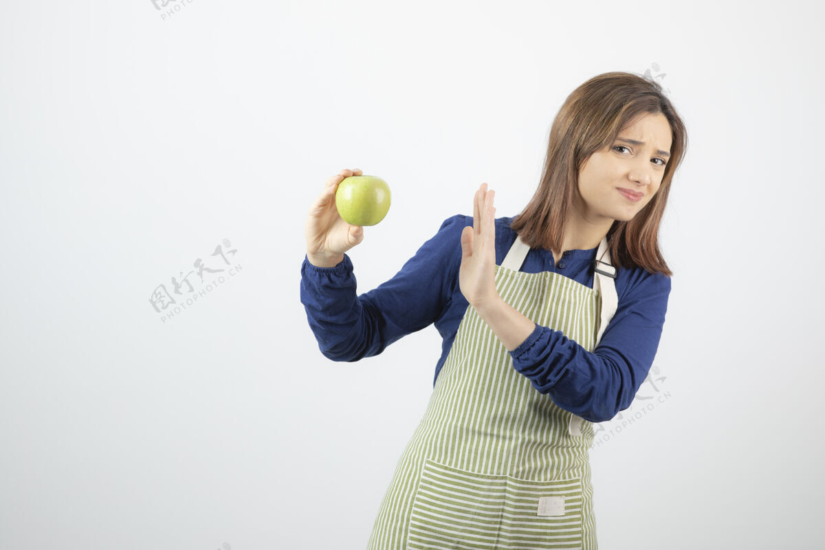 人穿着围裙的可爱的年轻女模特拒绝吃新鲜的绿色苹果水果年轻围裙