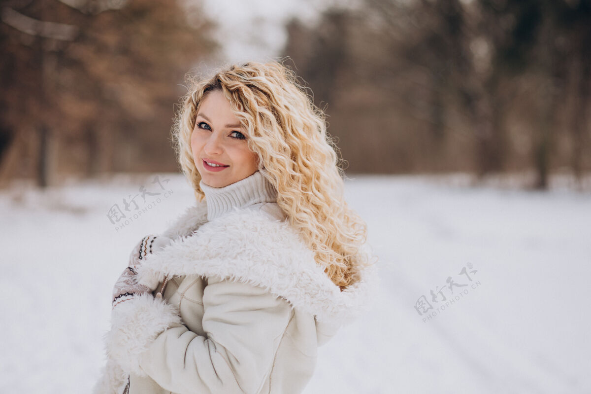 公园一个卷发的年轻女人在冬天的公园里散步看快乐的女人美丽