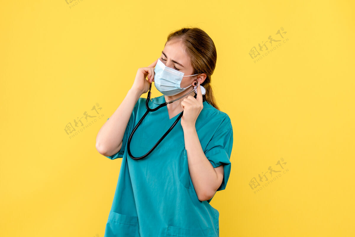 大流行正面图：女医生在黄色背景的健康病毒大流行病毒covid上磕耳朵仪器人专业