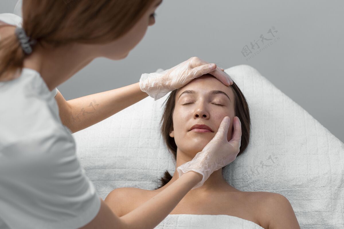 美容院美容师与女性客户在沙龙进行面部护理女人美容治疗面部护理