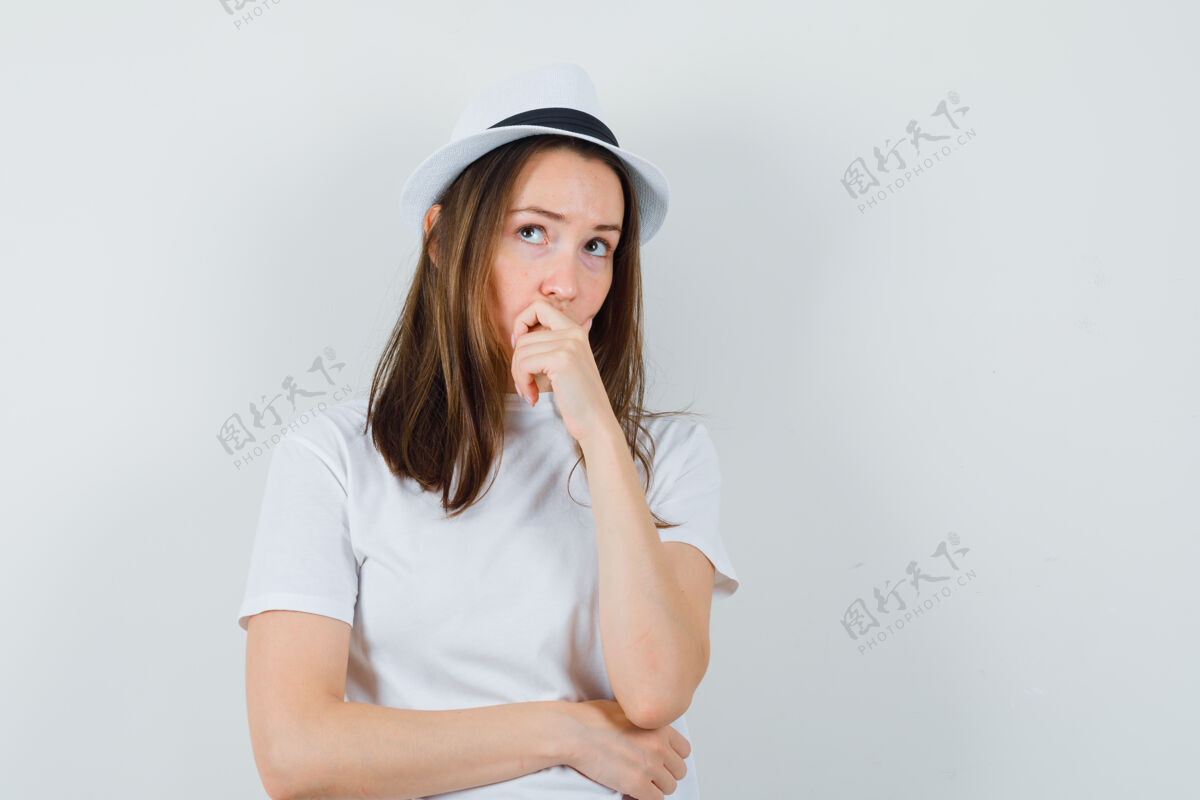 随意穿着白色t恤的年轻女孩 戴着帽子托着下巴 看上去很体贴 前视图快乐小小