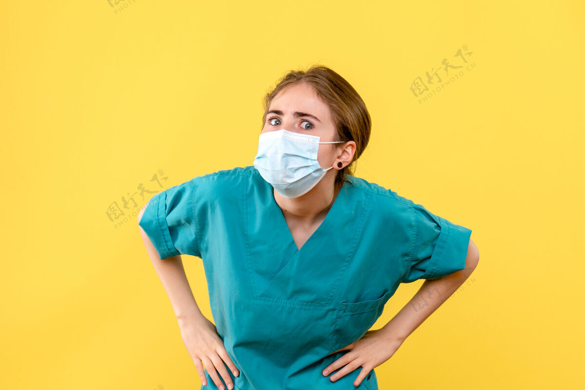 医院正面图女医生好奇地看着黄色背景的卫生院柯维德大流行封面男性面具