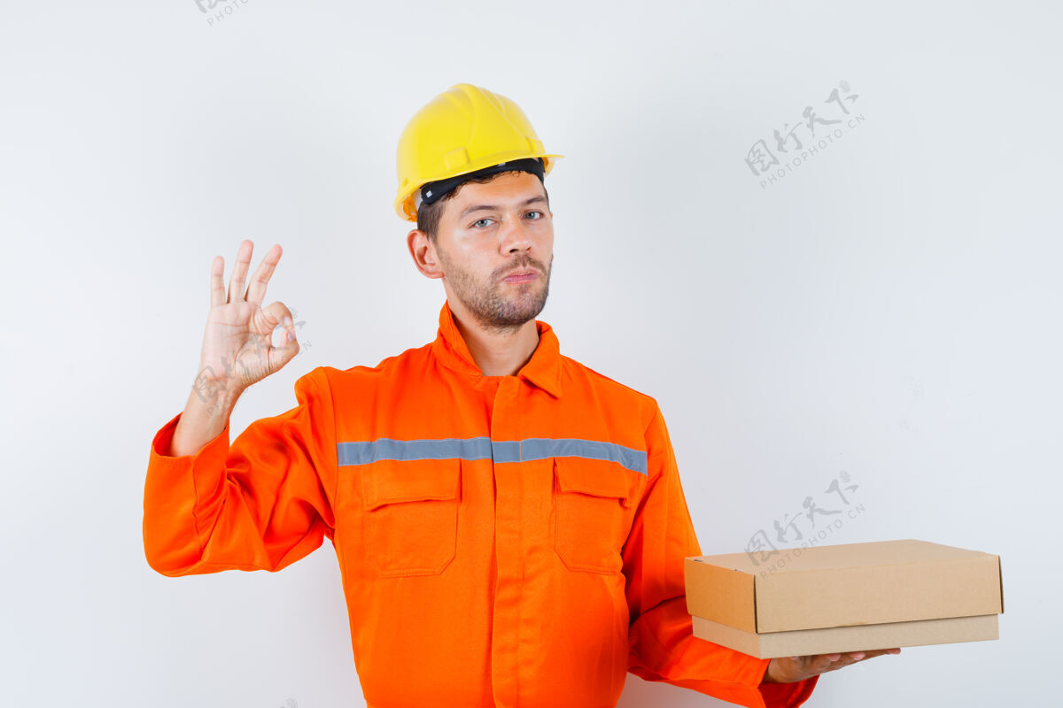 制服建筑工人拿着纸板箱 制服上显示ok标志 头盔正视图Ok团队人