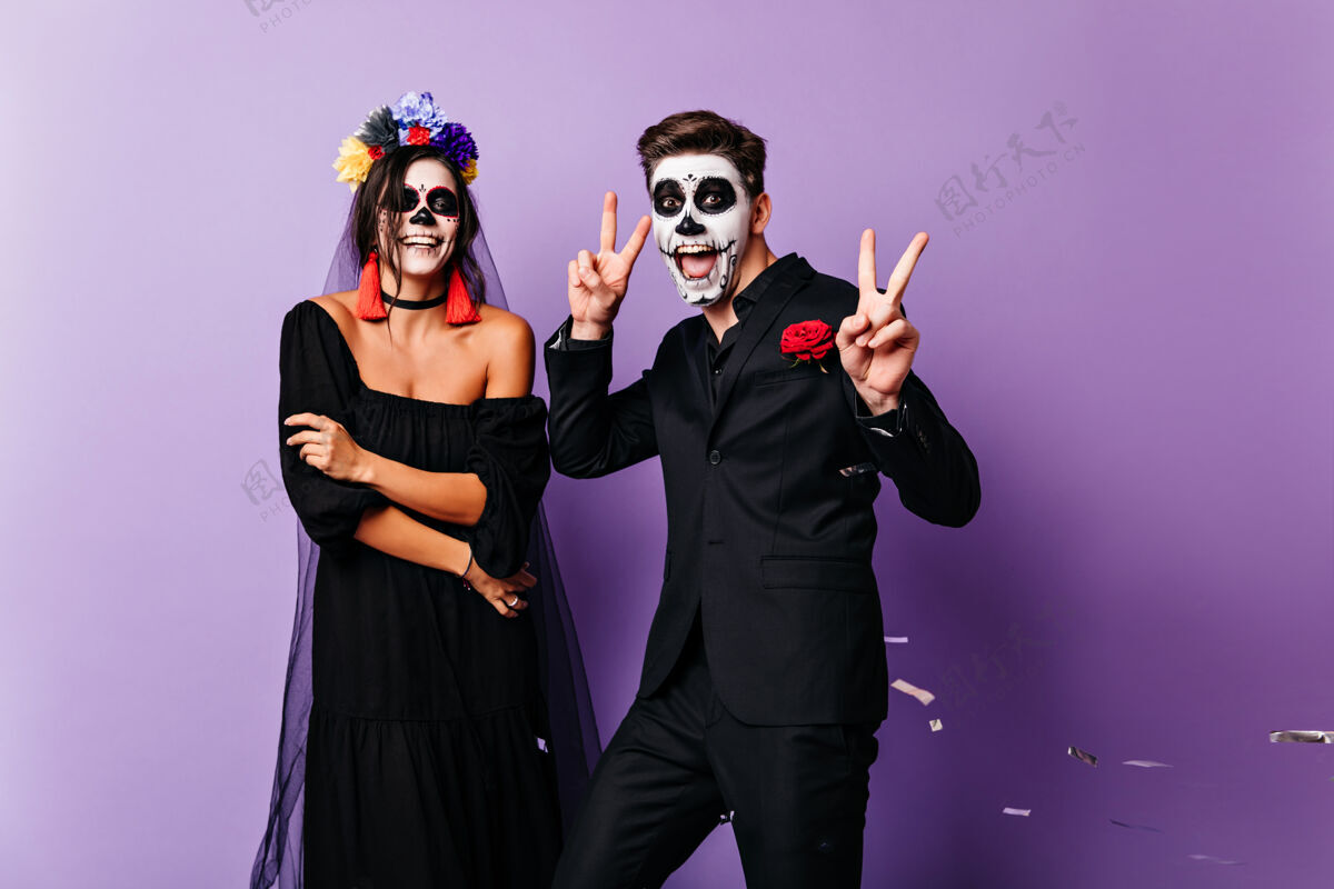 浪漫微笑的死去新娘在紫色背景上摆姿势两个僵尸在一起跳舞骷髅化妆舞会传统