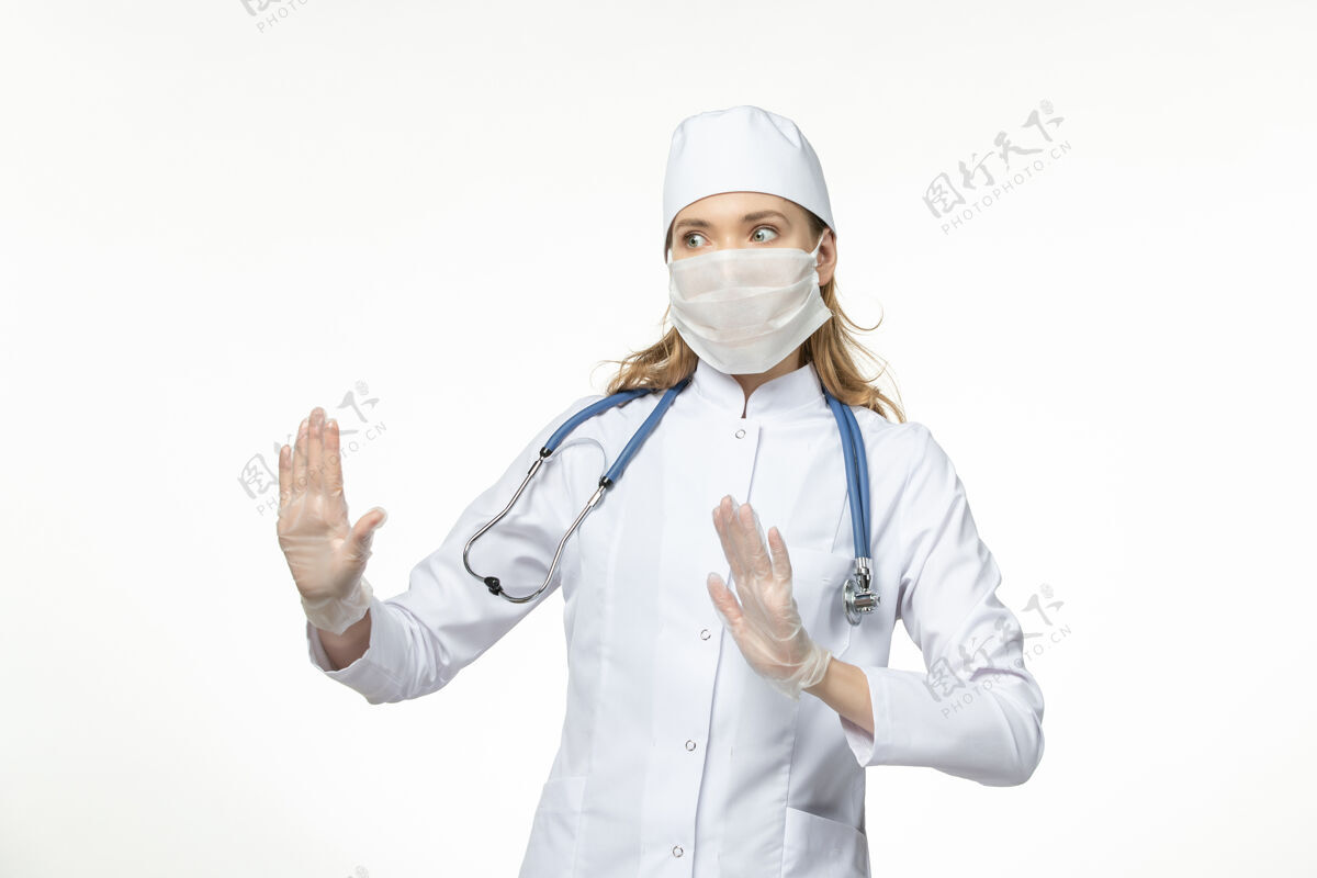 医疗器械正面图女医生穿着医疗服戴着口罩和手套因冠状病毒白墙大流行病毒病套装大流行面罩