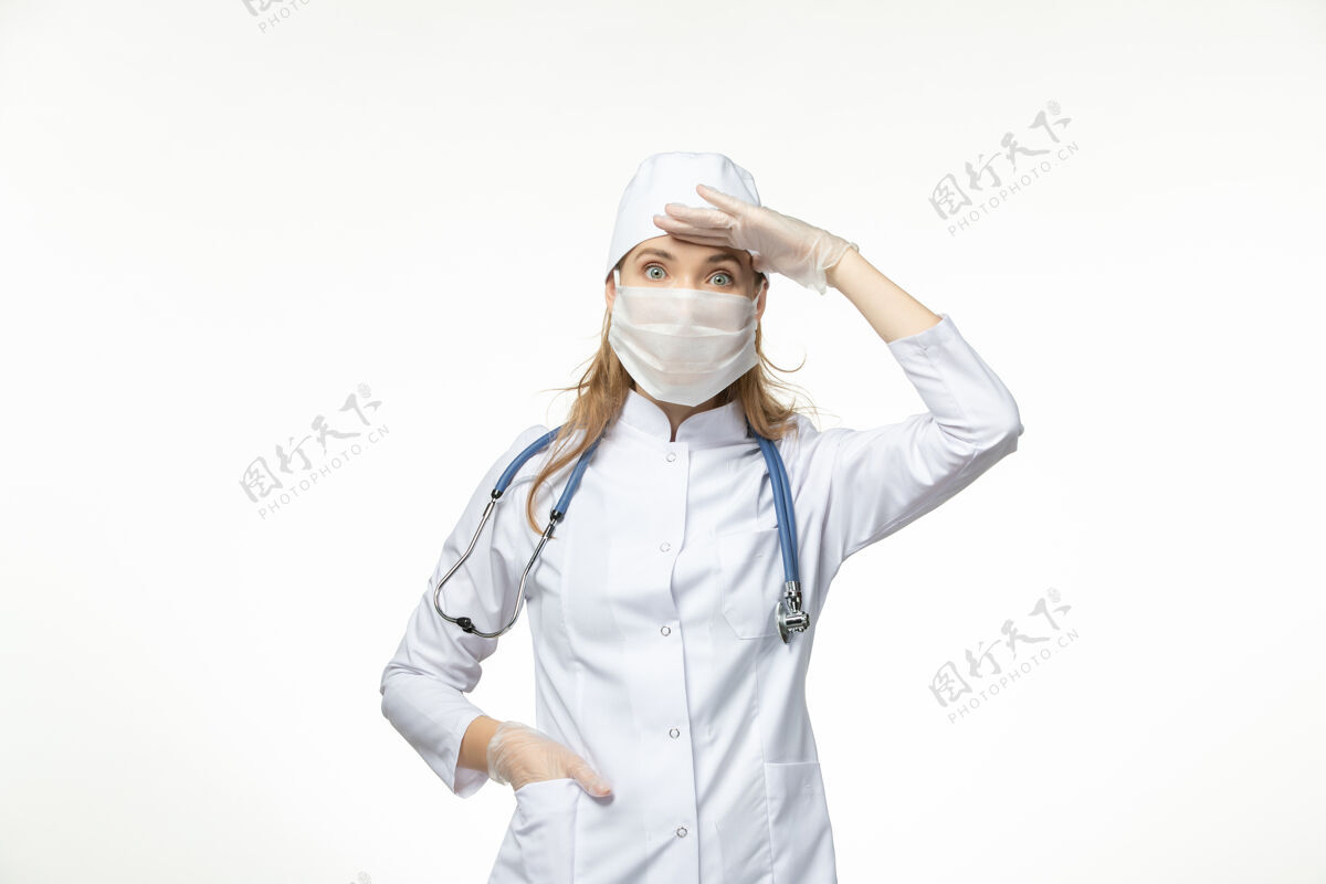 冠状病毒防护正面图女医生穿着医疗服 带着无菌口罩 因白墙上冠状病毒病大流行健康冠状病毒-套装面具正面