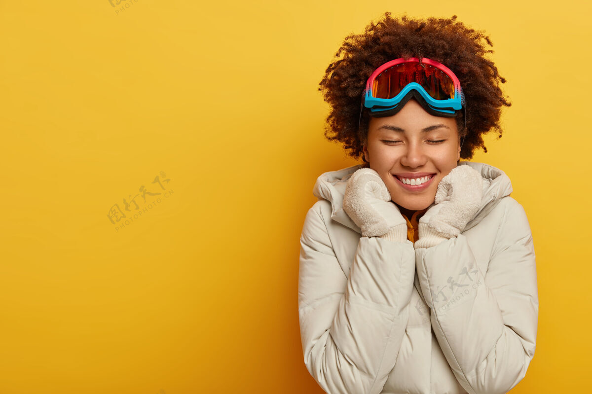 快乐快乐的非洲女人戴着滑雪面罩 温暖的针织手套和外套 喜欢户外活动快乐的女人穿着滑雪板夹克年轻保持