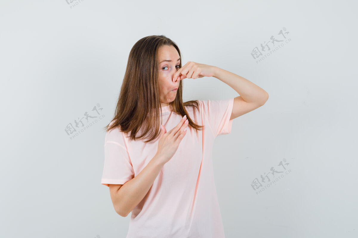 鼻子年轻女子捏鼻子因异味穿着粉色t恤 神情厌恶 前视图坏应有时尚