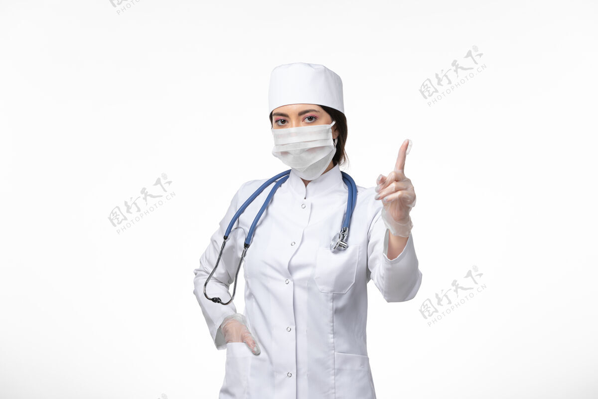冠状病毒防护正面图：女医生穿着白色无菌医疗服 戴着口罩 因为柯维德在白墙上冒充疾病柯维德大流行疾病姿势人员药品