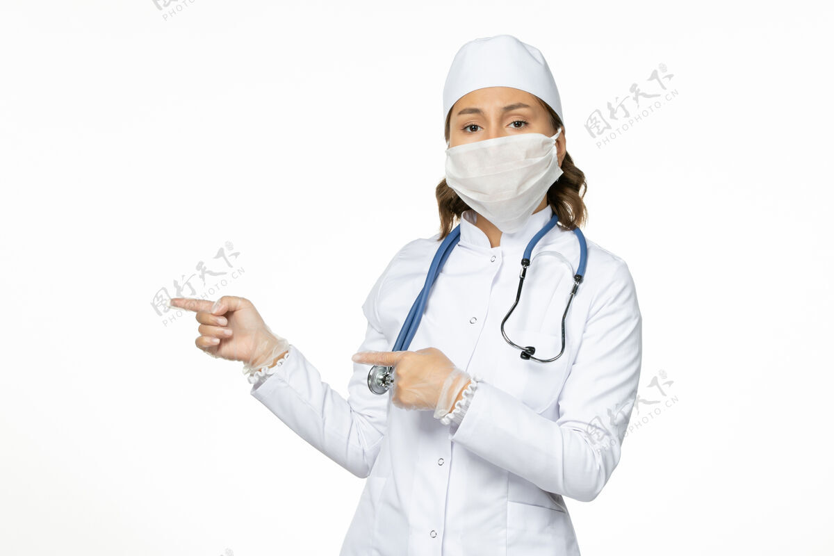 到期正面图女医生穿着白色医疗服 戴着口罩 因白色办公桌上的冠状病毒病大流行女性疾病病毒