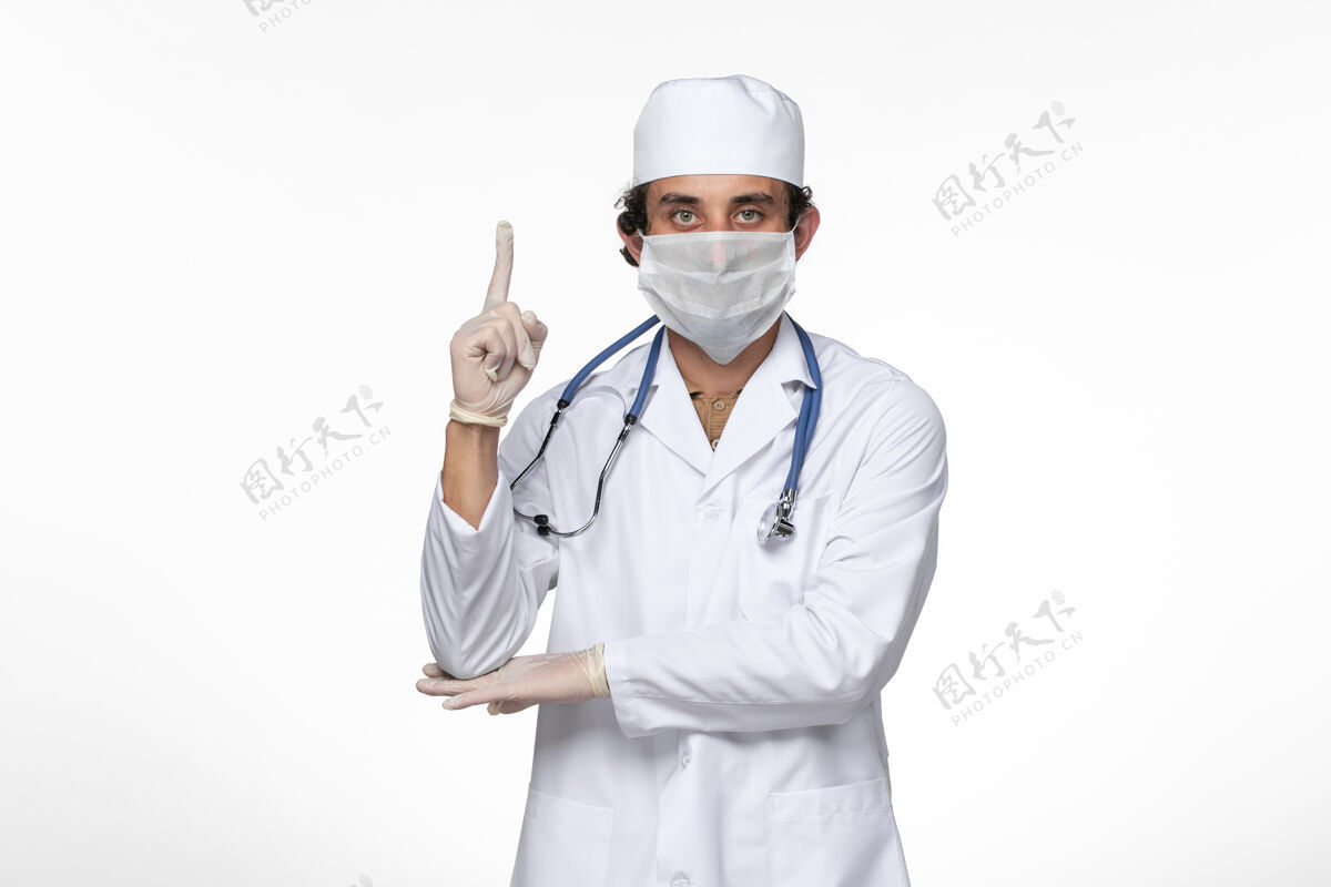 大流行正面图穿着医疗服的男医生 戴着无菌口罩 以防白墙病毒感染冠状病毒疾病穿着