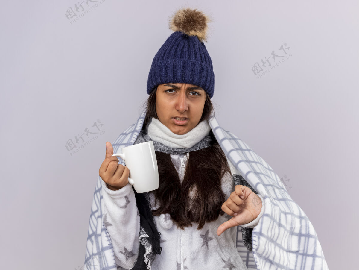 帽子未出嫁的生病的年轻女孩戴着冬天的帽子 围巾裹着格子呢 手里拿着一杯茶 拇指朝下围巾冬天拇指