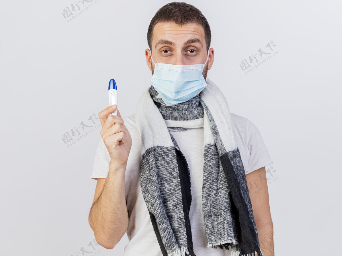 围巾看着镜头年轻的病人戴着医用口罩和围巾拿着温度计隔离在白色的男人医疗面具