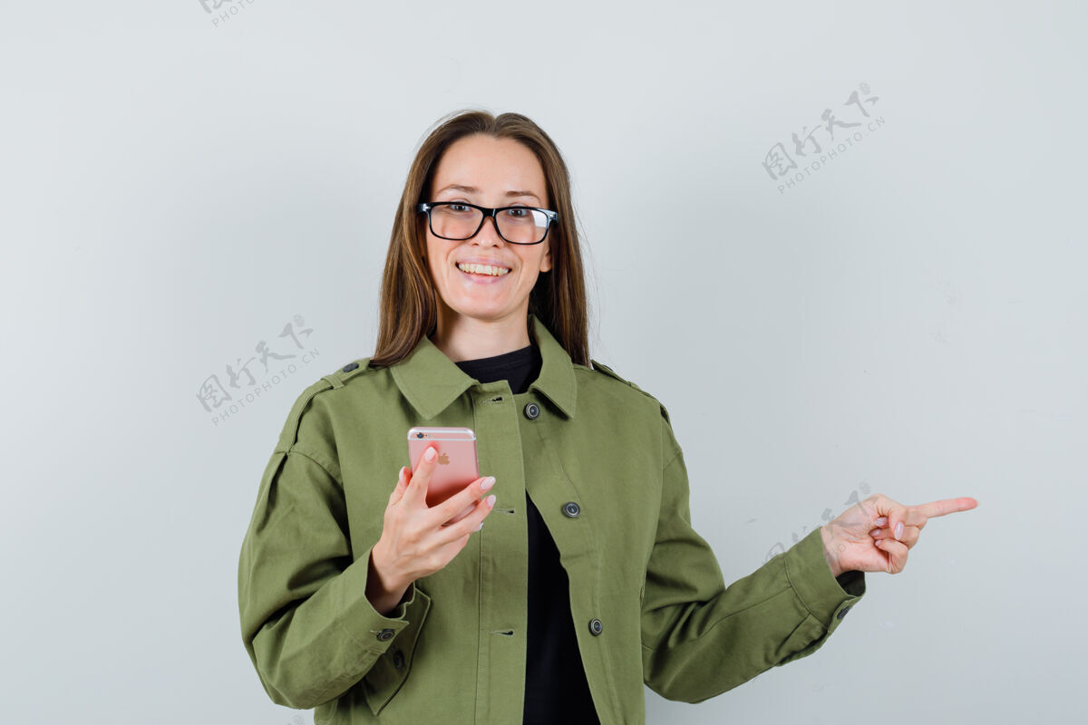 一旁穿着绿色夹克的年轻女子 戴着眼镜 一边拿着电话一边指着一边 正对着前方年轻肖像电话
